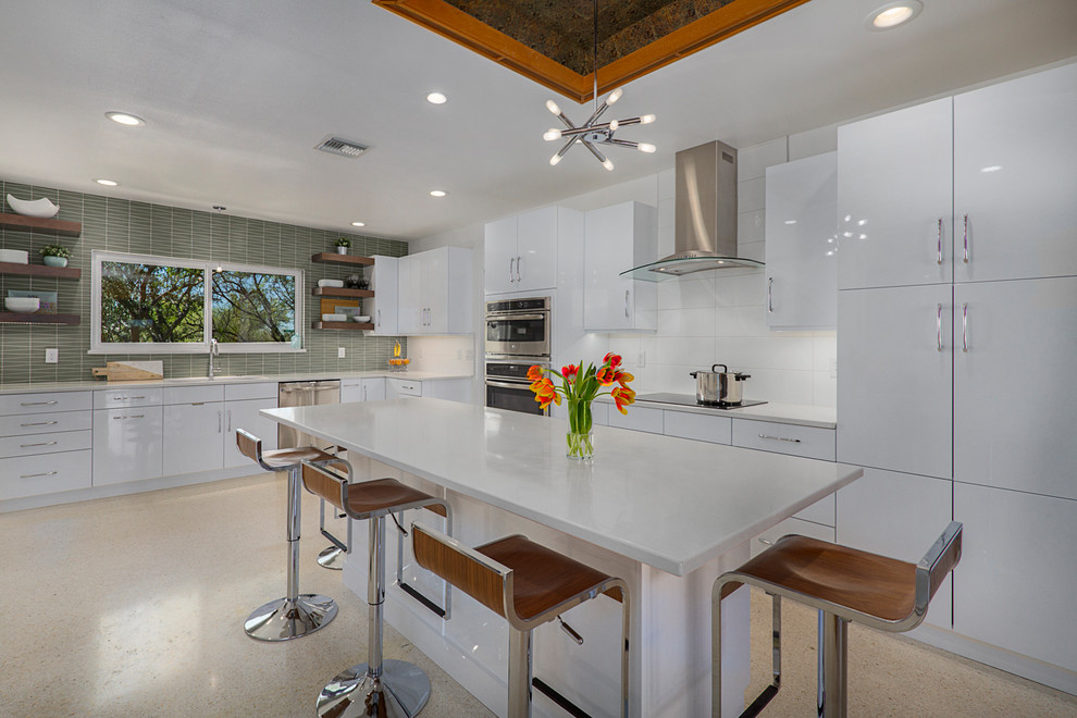 This is an example of a mid-sized midcentury galley separate kitchen in Phoenix with an undermount sink, flat-panel cabinets, white cabinets, quartz benchtops, green splashback, glass tile splashback, stainless steel appliances, terrazzo floors, with island, beige floor and white benchtop.