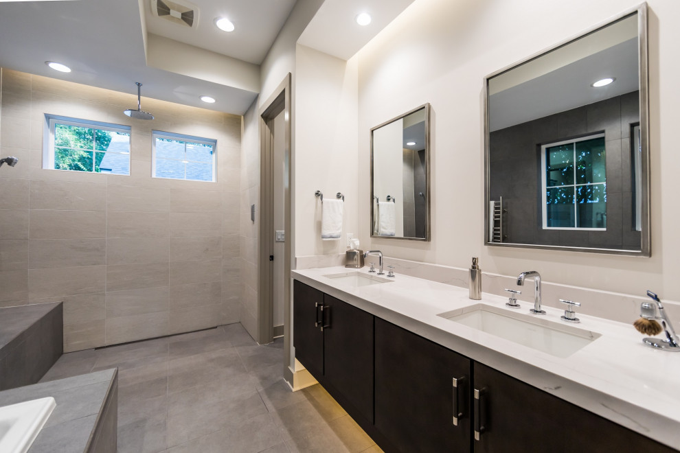 This is an example of a mid-sized country master bathroom in Jacksonville with flat-panel cabinets, brown cabinets, a drop-in tub, an open shower, a two-piece toilet, gray tile, porcelain tile, grey walls, medium hardwood floors, an undermount sink, engineered quartz benchtops, brown floor and white benchtops.