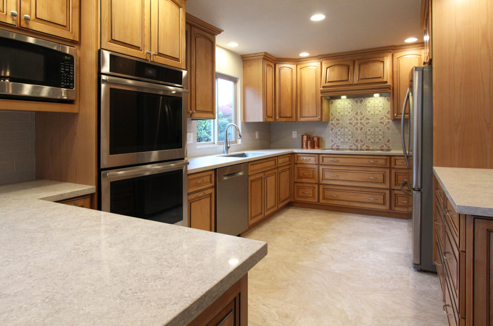 Example of a mid-sized u-shaped porcelain tile and beige floor eat-in kitchen design with an undermount sink, raised-panel cabinets, medium tone wood cabinets, quartz countertops, multicolored backsplash, ceramic backsplash, stainless steel appliances, a peninsula and multicolored countertops
