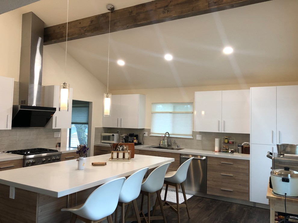 Design ideas for a mid-sized modern l-shaped separate kitchen in San Francisco with an undermount sink, quartzite benchtops, beige splashback, glass tile splashback, black appliances, laminate floors, with island, white benchtop, flat-panel cabinets, white cabinets and brown floor.