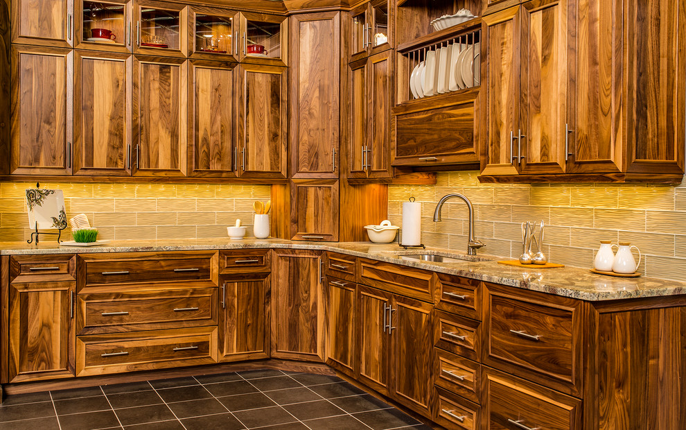 Example of a mid-sized classic ceramic tile and gray floor kitchen design with an undermount sink, recessed-panel cabinets, dark wood cabinets, granite countertops, brown backsplash and glass tile backsplash