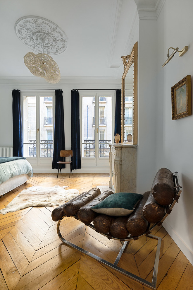 Photo of a large scandinavian master bedroom in Paris with white walls, light hardwood floors, no fireplace and brown floor.
