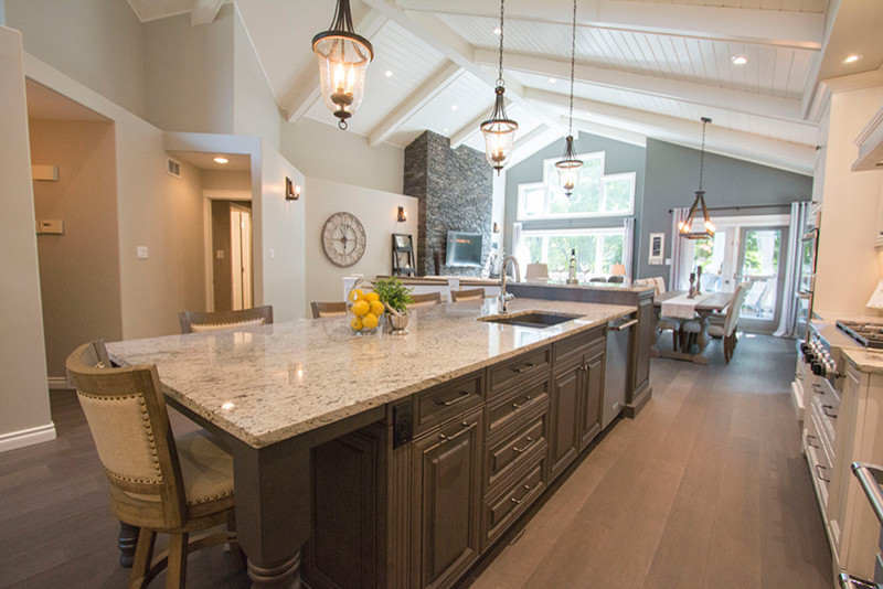 Inspiration for a large transitional l-shaped eat-in kitchen remodel with a double-bowl sink, shaker cabinets, white cabinets, beige backsplash, stainless steel appliances and an island