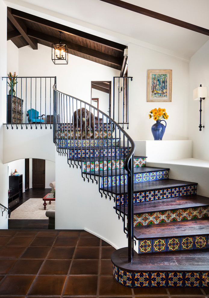 Photo of a mid-sized mediterranean wood curved staircase in Santa Barbara with tile risers and metal railing.