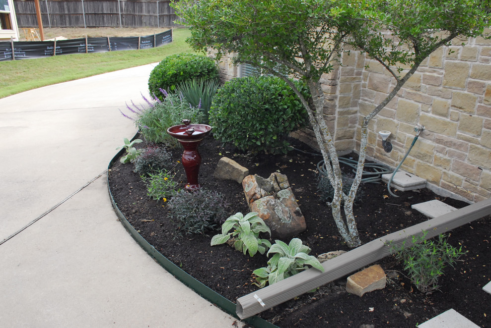 Photo of a mid-sized front yard full sun xeriscape for spring in Dallas with with flowerbed and concrete pavers.