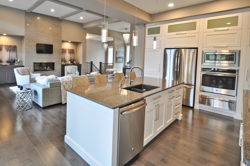 Inspiration for a mid-sized transitional l-shaped light wood floor and brown floor eat-in kitchen remodel in Edmonton with an undermount sink, shaker cabinets, white cabinets, quartzite countertops, yellow backsplash, glass tile backsplash, stainless steel appliances and an island