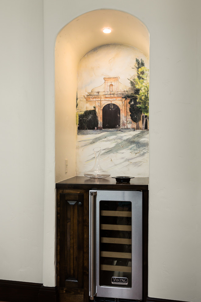 This is an example of a mediterranean home bar in Los Angeles with raised-panel cabinets and dark wood cabinets.