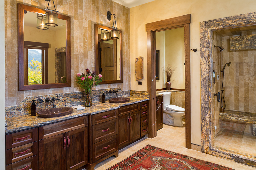 Design ideas for a large country master bathroom in Other with stone tile, shaker cabinets, dark wood cabinets, an alcove shower, a one-piece toilet, beige walls, limestone floors, a vessel sink, granite benchtops, beige floor and an open shower.