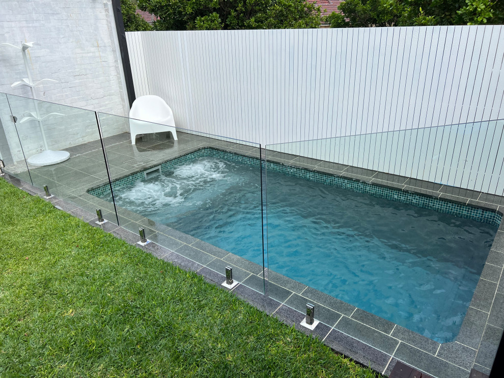 Ispirazione per una piscina moderna rettangolare di medie dimensioni e dietro casa con paesaggistica bordo piscina e pavimentazioni in pietra naturale