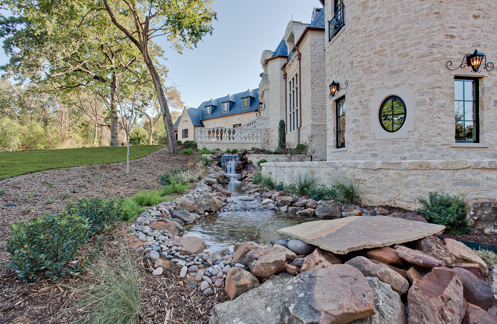 Photo of an expansive traditional three-storey beige house exterior in Dallas with stone veneer, a hip roof and a tile roof.