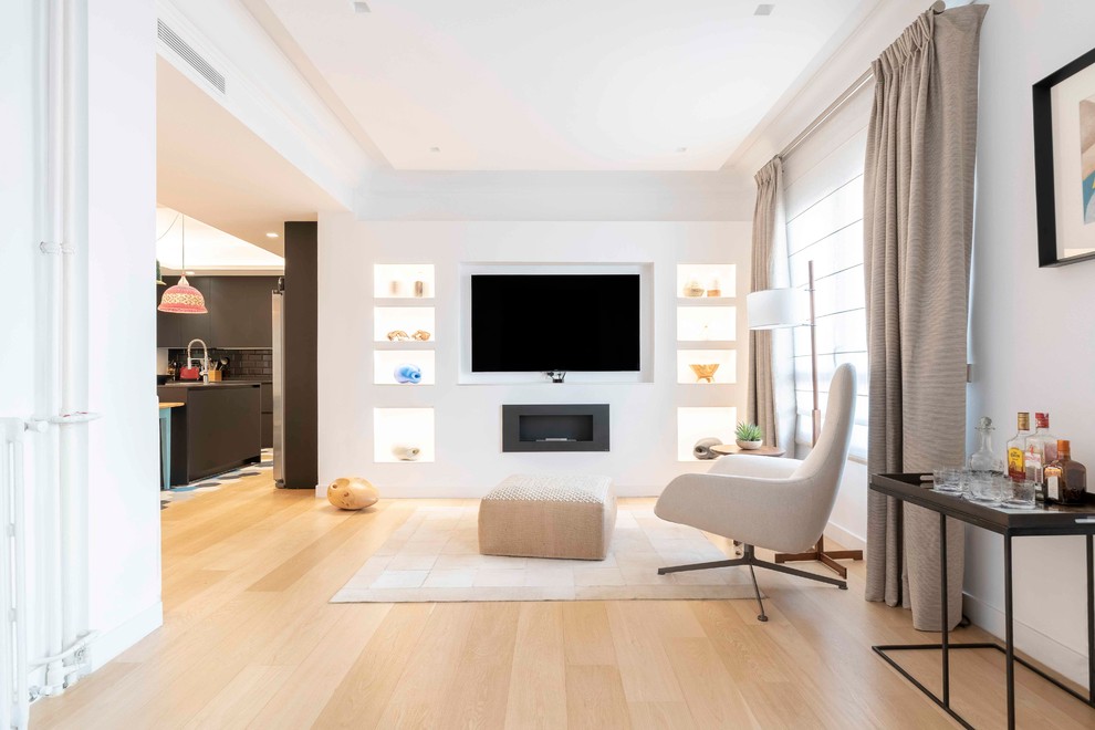 Photo of a contemporary open concept living room in Madrid with a home bar, white walls, light hardwood floors, a ribbon fireplace, a wall-mounted tv and beige floor.