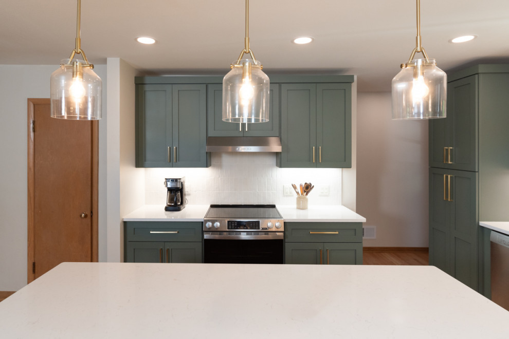 Example of a transitional light wood floor kitchen design with shaker cabinets, green cabinets, quartz countertops, white backsplash, ceramic backsplash and an island