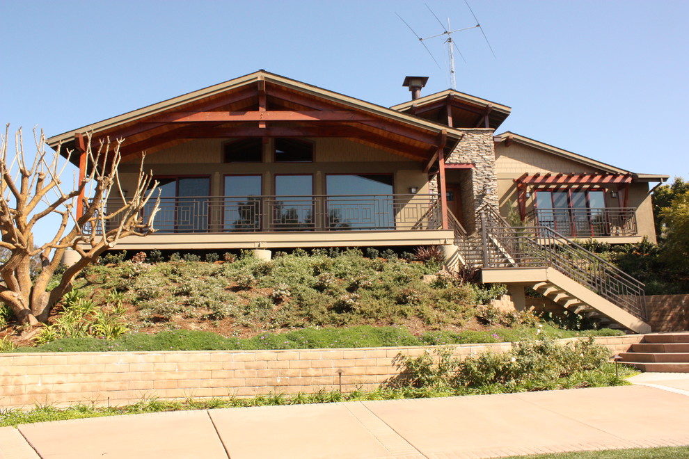 This is an example of a large arts and crafts one-storey green house exterior in San Diego with a gable roof, stone veneer and a shingle roof.