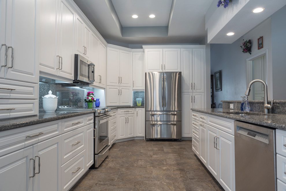 Inspiration for a mid-sized traditional l-shaped open plan kitchen in Tampa with an undermount sink, raised-panel cabinets, white cabinets, granite benchtops, blue splashback, stone slab splashback, stainless steel appliances, porcelain floors and with island.