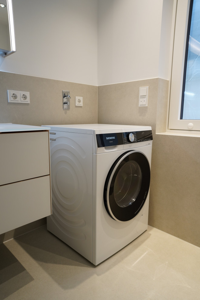 Mittelgroßes Modernes Duschbad mit flächenbündigen Schrankfronten, weißen Schränken, bodengleicher Dusche, Wandtoilette, beigen Fliesen, Steinfliesen, weißer Wandfarbe, Wandwaschbecken, Glaswaschbecken/Glaswaschtisch, beigem Boden, Falttür-Duschabtrennung, weißer Waschtischplatte, Einzelwaschbecken und schwebendem Waschtisch in München