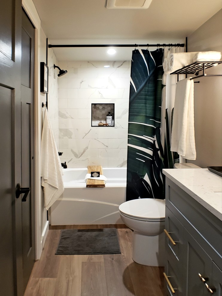 Inspiration for a mid-sized contemporary kids bathroom in Seattle with shaker cabinets, grey cabinets, an alcove tub, an alcove shower, a two-piece toilet, multi-coloured tile, porcelain tile, grey walls, an undermount sink, engineered quartz benchtops, brown floor, a shower curtain, white benchtops and light hardwood floors.