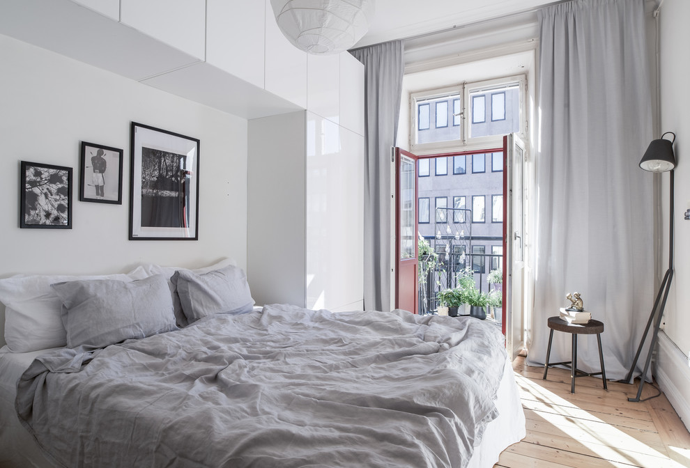 Mid-sized scandinavian master bedroom in Stockholm with white walls and light hardwood floors.