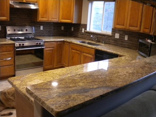 Elegant kitchen photo with granite countertops and glass sheet backsplash