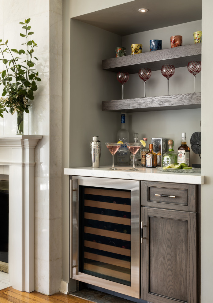 Design ideas for a small transitional single-wall home bar in New York with flat-panel cabinets, grey cabinets, marble benchtops, light hardwood floors and white benchtop.