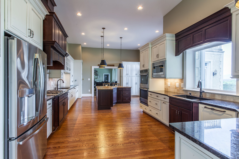 Eat-in kitchen - huge transitional medium tone wood floor eat-in kitchen idea in DC Metro with raised-panel cabinets, granite countertops, stainless steel appliances and an island