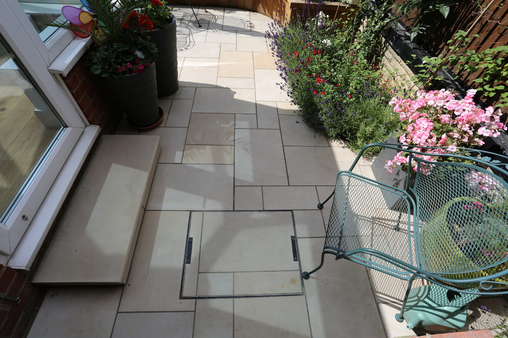Photo of a small modern backyard full sun formal garden in London with a fire feature and natural stone pavers.