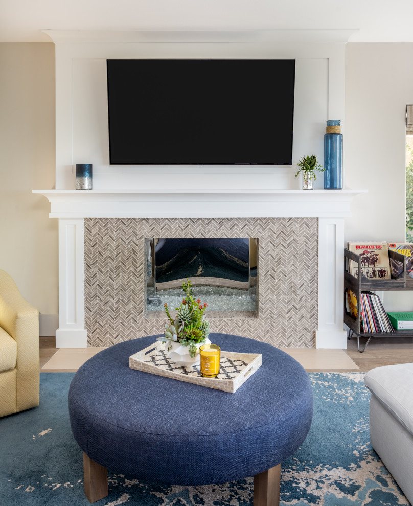 Photo of a mid-sized beach style open concept family room in Orange County with grey walls, light hardwood floors, a stone fireplace surround, a wall-mounted tv and beige floor.