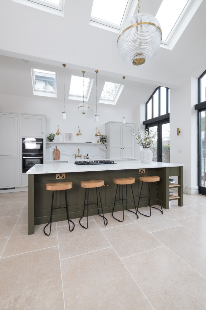 Example of a large classic single-wall porcelain tile and vaulted ceiling open concept kitchen design in Cardiff with a farmhouse sink, shaker cabinets, light wood cabinets, quartzite countertops, white backsplash, stone slab backsplash, stainless steel appliances, an island and white countertops