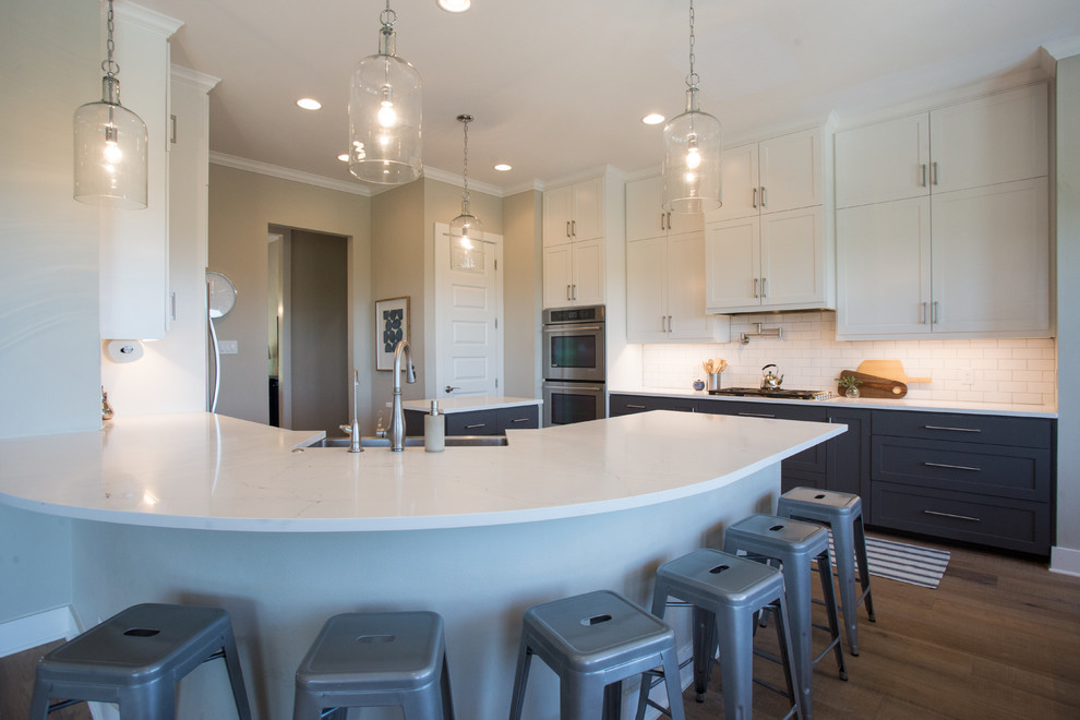 Transitional light wood floor and beige floor eat-in kitchen photo in Austin with a farmhouse sink, shaker cabinets, white cabinets, quartz countertops, white backsplash, subway tile backsplash, stainless steel appliances and an island