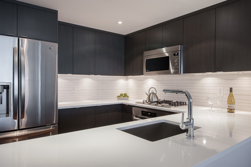 Example of a mid-sized minimalist u-shaped open concept kitchen design in Vancouver with an undermount sink, flat-panel cabinets, black cabinets, quartzite countertops, white backsplash, stainless steel appliances and a peninsula