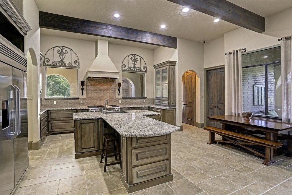 Inspiration for an expansive transitional l-shaped eat-in kitchen in Houston with an undermount sink, recessed-panel cabinets, medium wood cabinets, granite benchtops, brown splashback, stone tile splashback, stainless steel appliances, ceramic floors, with island, beige floor and grey benchtop.