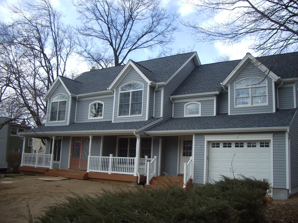 This is an example of a mid-sized traditional two-storey grey exterior in New York with vinyl siding and a gable roof.