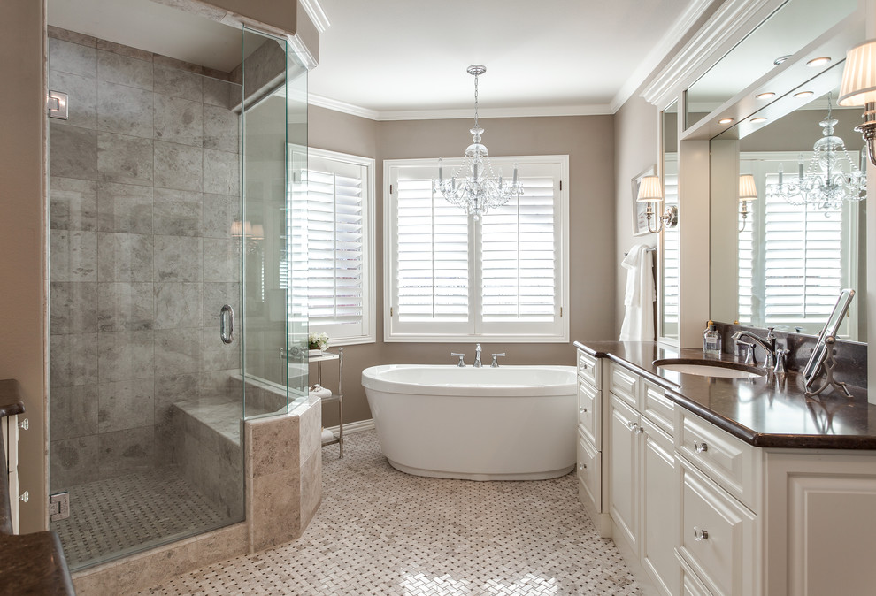Photo of a large transitional master bathroom in Denver with an undermount sink, raised-panel cabinets, white cabinets, marble benchtops, a freestanding tub, a curbless shower, beige tile, mosaic tile, brown walls and mosaic tile floors.