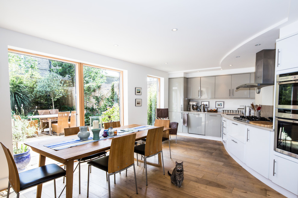 Inspiration for a mid-sized contemporary single-wall eat-in kitchen in Cambridgeshire with a drop-in sink, flat-panel cabinets, grey cabinets, stainless steel appliances, light hardwood floors, no island and brown floor.