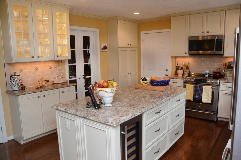 This is an example of a mid-sized u-shaped eat-in kitchen in DC Metro with a single-bowl sink, recessed-panel cabinets, yellow cabinets, quartz benchtops, beige splashback, stainless steel appliances, medium hardwood floors, with island and brown floor.