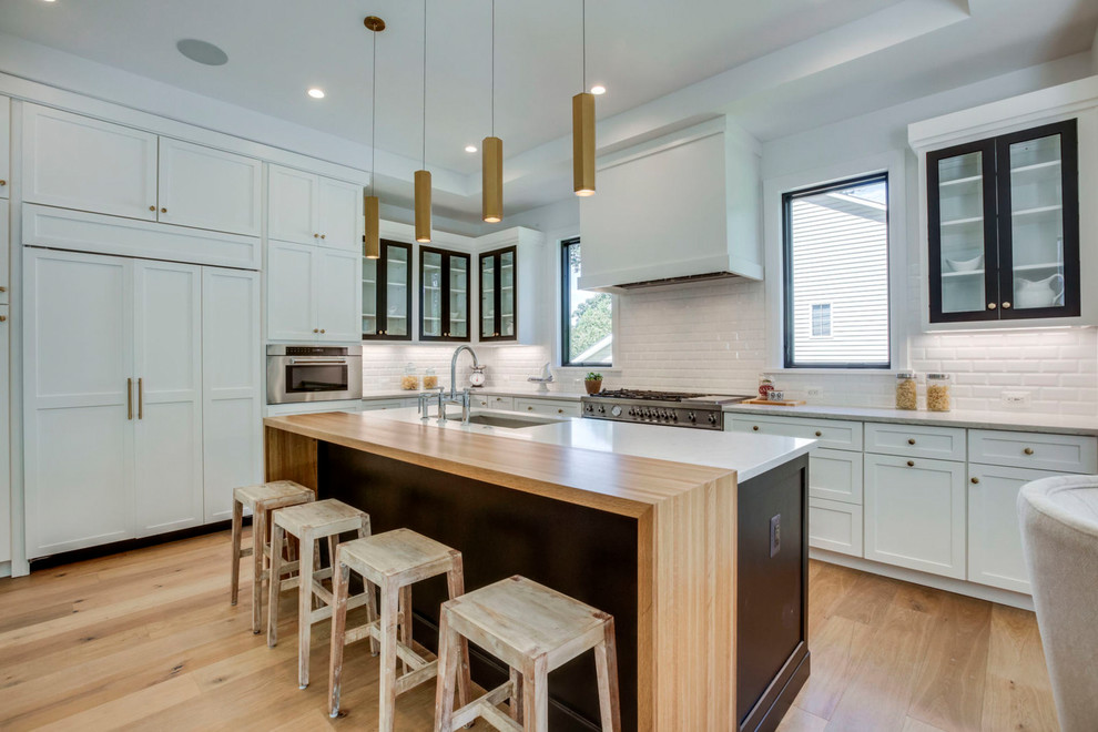 Design ideas for a transitional l-shaped kitchen in DC Metro with shaker cabinets, white splashback, subway tile splashback, with island, white benchtop, an undermount sink, panelled appliances and light hardwood floors.