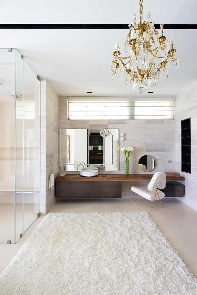 Photo of a contemporary bathroom in Miami with flat-panel cabinets, a curbless shower, beige tile, beige walls, a vessel sink, wood benchtops, dark wood cabinets and a hinged shower door.