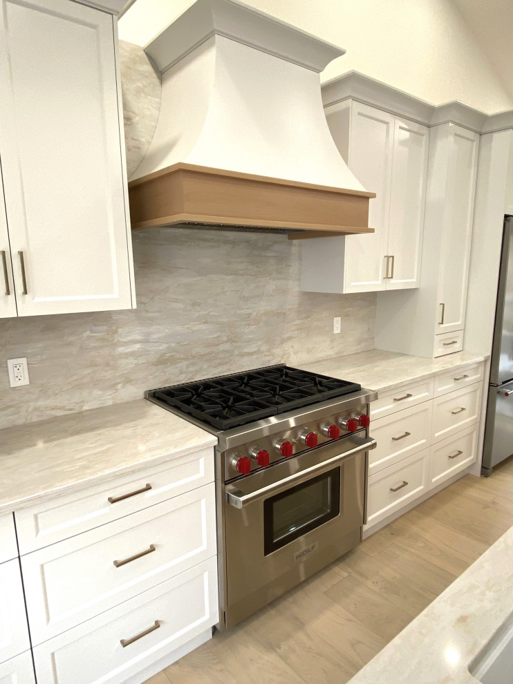 Small transitional galley light wood floor and vaulted ceiling open concept kitchen photo in Toronto with an undermount sink, recessed-panel cabinets, white cabinets, quartz countertops, quartz backsplash and stainless steel appliances
