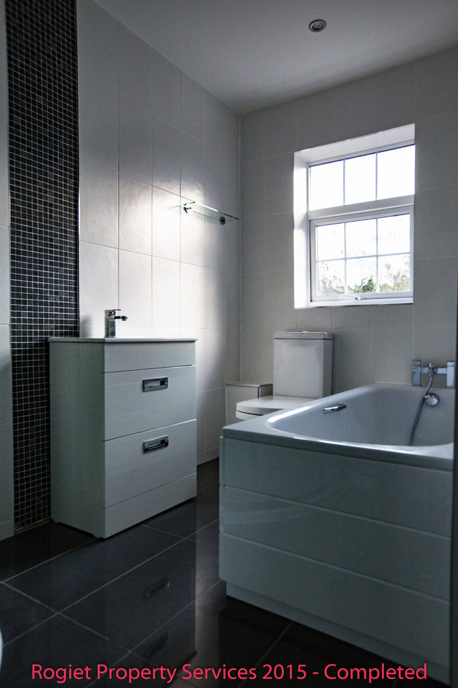 Medium sized contemporary family bathroom in Other with a built-in sink, flat-panel cabinets, white cabinets, an alcove bath, an alcove shower, a two-piece toilet, white tiles, ceramic tiles, white walls and porcelain flooring.