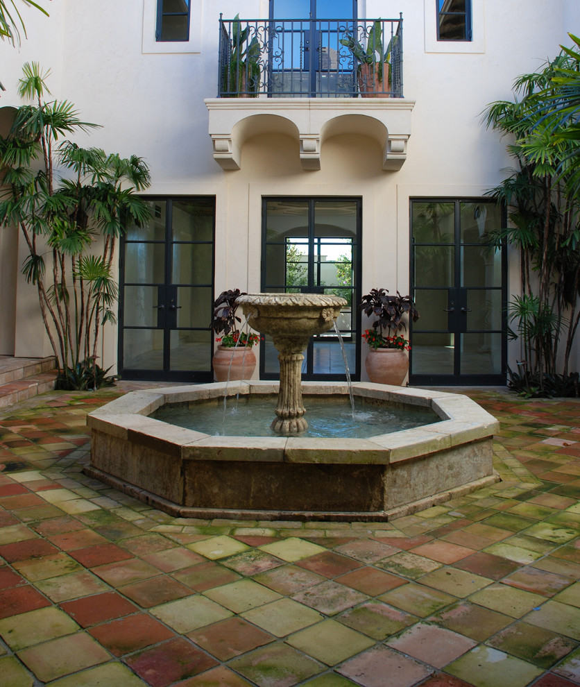 This is an example of a large mediterranean backyard partial sun garden in New York with a water feature and natural stone pavers.
