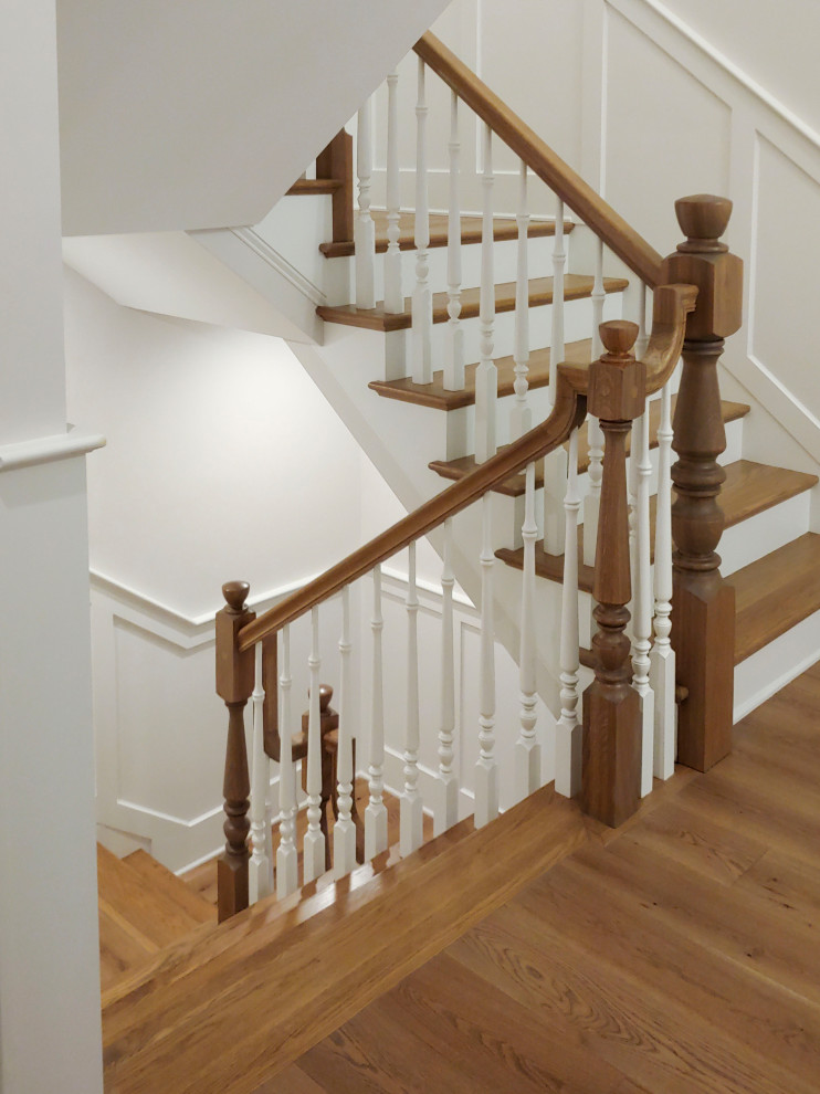 Mid-sized traditional wood u-shaped staircase in DC Metro with painted wood risers, wood railing and decorative wall panelling.