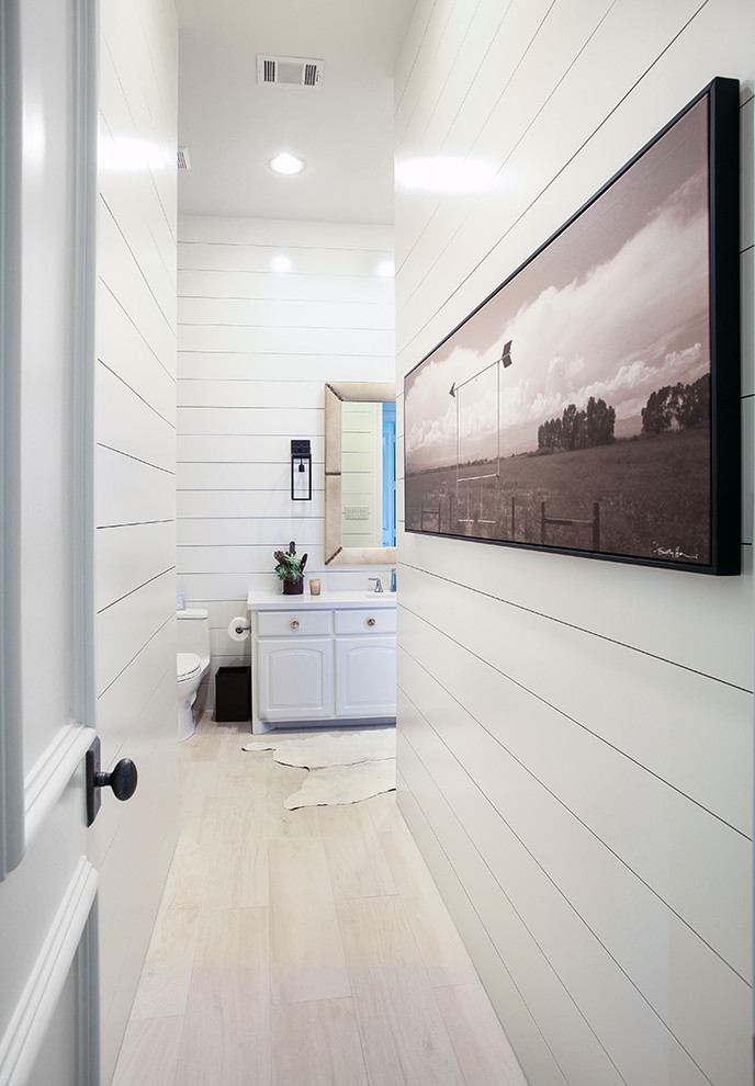 This is an example of a transitional bathroom in Dallas with white cabinets, white walls and light hardwood floors.