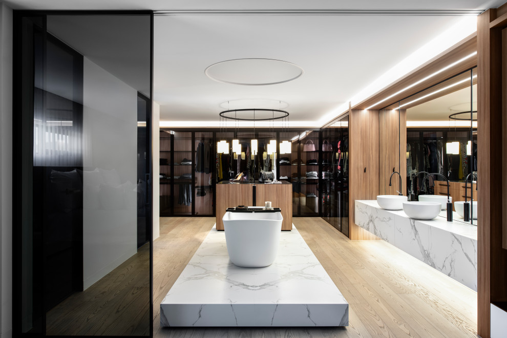 This is an example of an expansive contemporary master bathroom in Sydney with white cabinets, a freestanding tub, a double shower, medium hardwood floors, a vessel sink, marble benchtops, a hinged shower door, an enclosed toilet, a double vanity and a floating vanity.