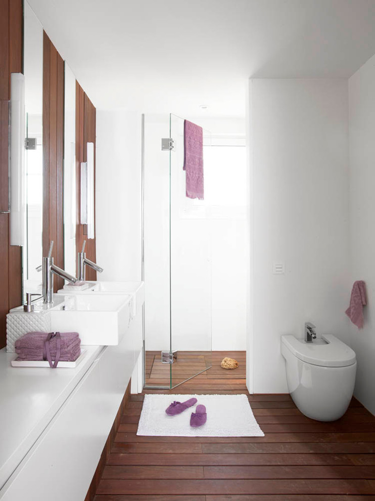 Inspiration for a mid-sized contemporary 3/4 bathroom in Barcelona with a vessel sink, flat-panel cabinets, white cabinets, an alcove shower, a wall-mount toilet, white tile, white walls and dark hardwood floors.