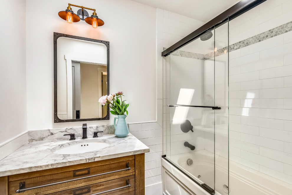 This is an example of a mid-sized country kids bathroom in DC Metro with louvered cabinets, medium wood cabinets, a hot tub, a shower/bathtub combo, a one-piece toilet, white tile, ceramic tile, white walls, ceramic floors, an undermount sink, granite benchtops, black floor, a sliding shower screen and grey benchtops.