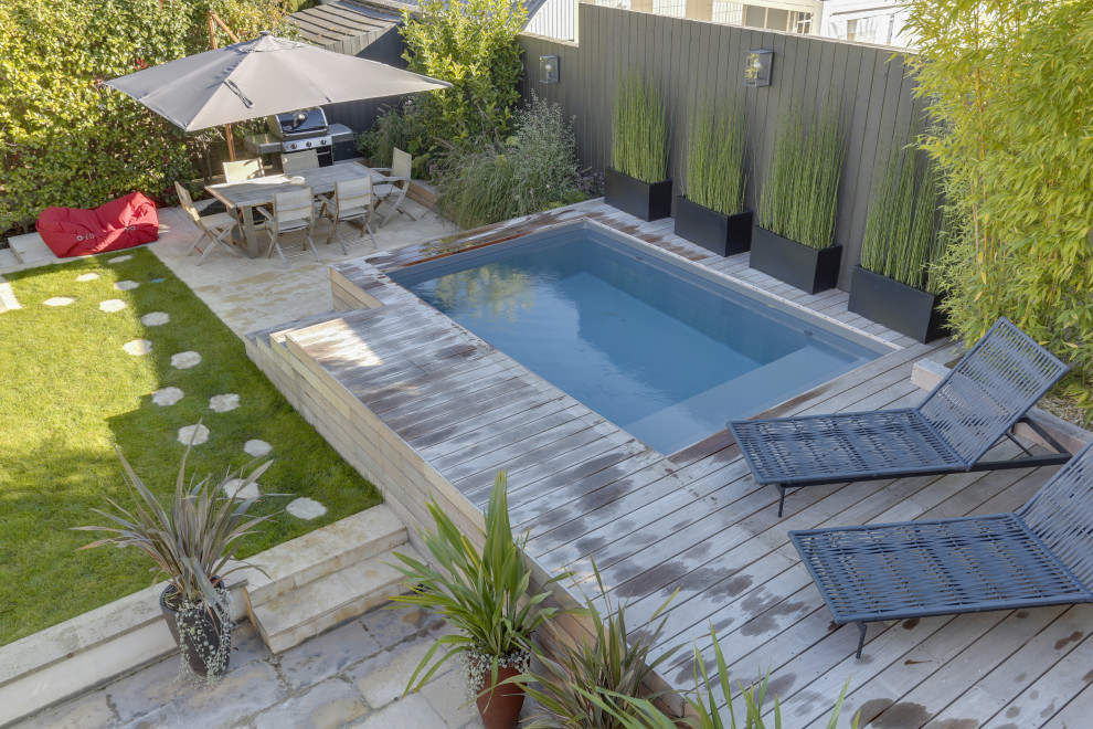 Cette photo montre un petit piscine avec aménagement paysager avant tendance rectangle avec une terrasse en bois.