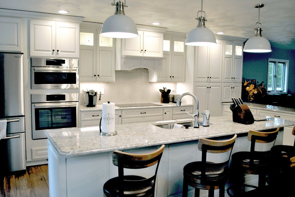 Inspiration for a transitional l-shaped medium tone wood floor open concept kitchen remodel in St Louis with raised-panel cabinets, white cabinets, granite countertops, white backsplash, ceramic backsplash, stainless steel appliances and an island