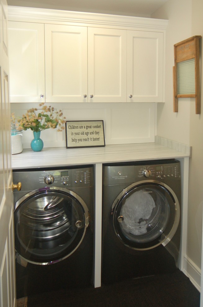 Photo of a mid-sized traditional single-wall dedicated laundry room in New York with an utility sink, flat-panel cabinets, white cabinets, marble benchtops, grey walls, carpet and a side-by-side washer and dryer.