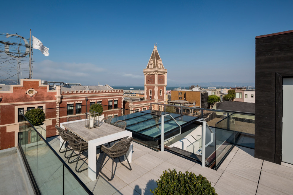 Cette image montre une terrasse sur le toit minimaliste avec des solutions pour vis-à-vis, aucune couverture et un garde-corps en verre.