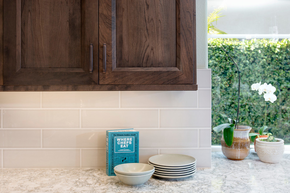 Open concept kitchen - huge transitional l-shaped porcelain tile open concept kitchen idea in Tampa with a single-bowl sink, recessed-panel cabinets, dark wood cabinets, soapstone countertops, beige backsplash, glass sheet backsplash, stainless steel appliances and an island