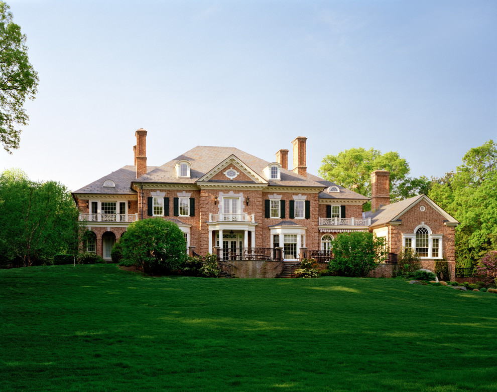 Expansive traditional three-storey brick red house exterior in New York with a hip roof and a shingle roof.